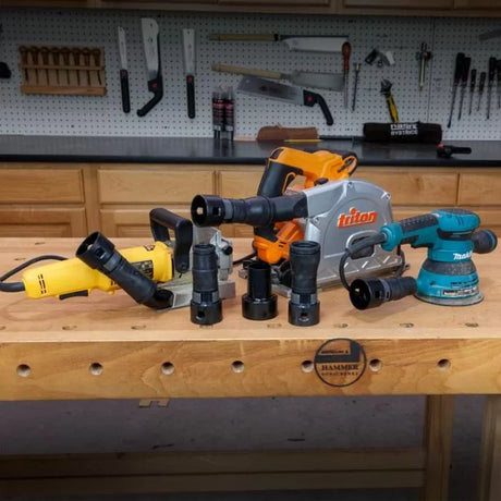 Woodworking power tools with dust collection adapters on workshop bench