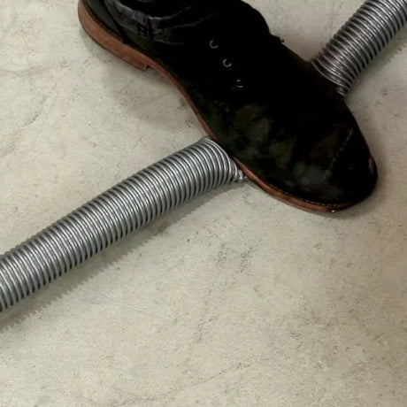 Heavy-duty dust collection hose on workshop floor with a shoe stepping on it