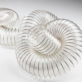 Clear flexible dust collection hose for woodworking, coiled on white background