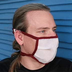 Man wearing a white dust protection mask with red trim, side view, blue background