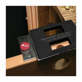 Woodworking door latch plate jig with metal template and adjustment knob attached to a door edge.