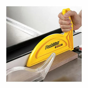 Yellow push stick guiding wood on a table saw for woodworking safety