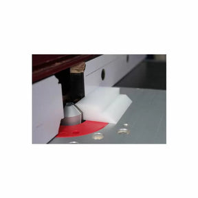 Router table setup with white plastic push block, router bit, and fence for woodworking safety.