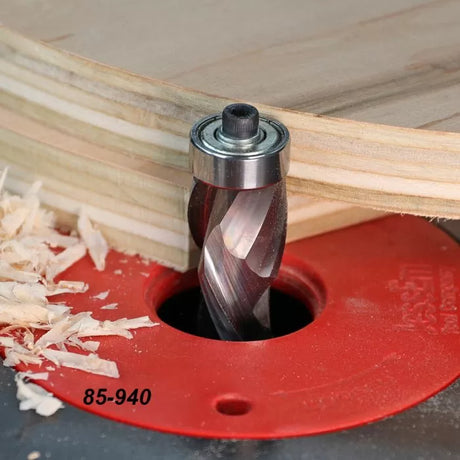 Spiral flush trim router bit cutting plywood on a red router table plate