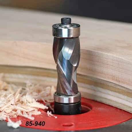 Spiral flush trim router bit cutting wood on a router table with wood shavings nearby