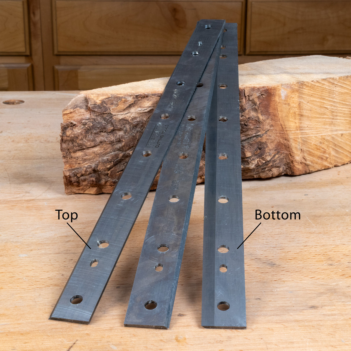 Two metal brackets on a wooden surface with labeled top and bottom.