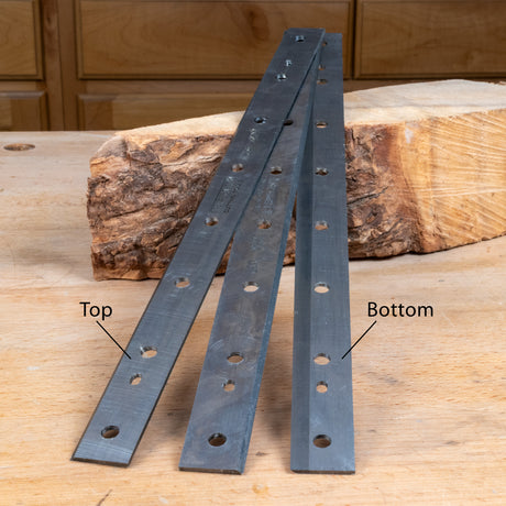 Two metal brackets on a wooden surface with labeled top and bottom.