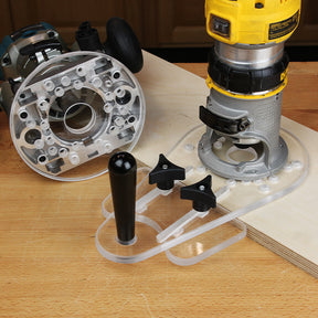 Clear acrylic router base plate with handle and knobs next to routers on woodworking bench