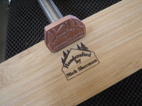 Wood branding iron marking handcrafted woodworking piece on light wood surface