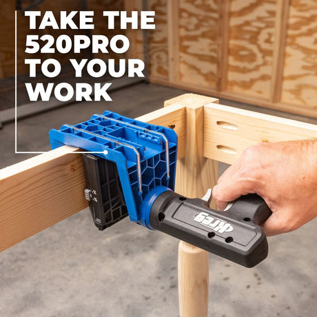 Hand holding a Kreg Pocket Hole drill guide on a wooden surface.