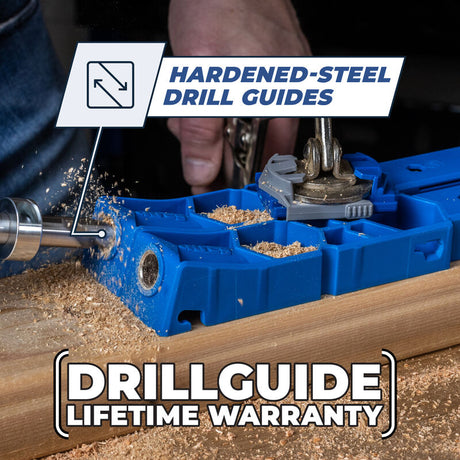 Close-up of a blue drill guide jig with hardened-steel guides in use on wood, wood shavings visible.