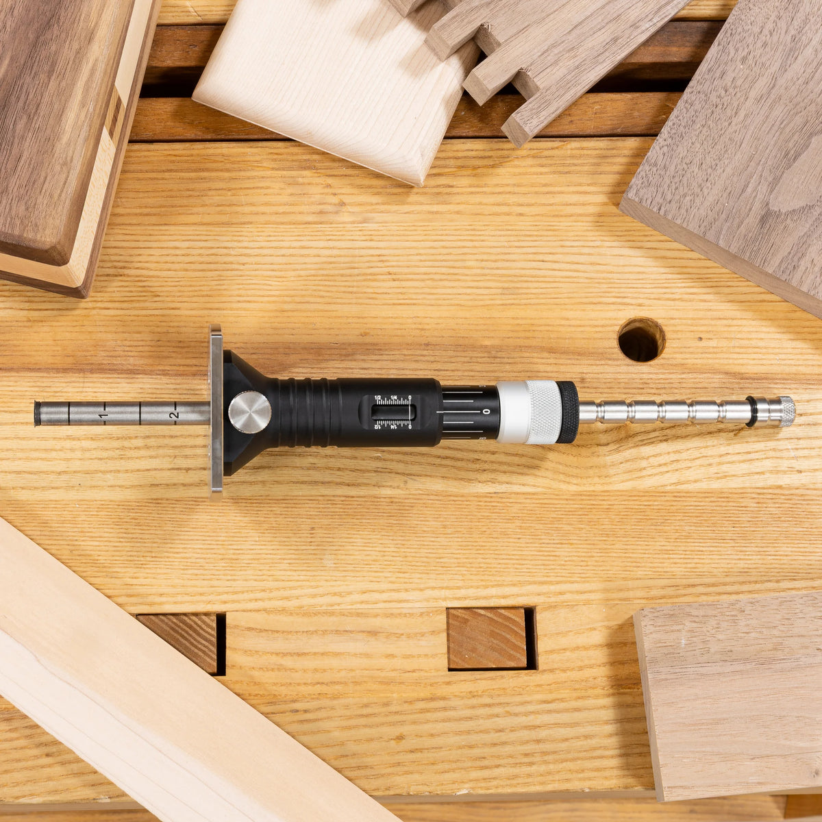 JessEm Wood Sabre II marking gauge resting on a workbench with dovetail joints in the background