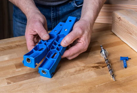 Hands holding blue pocket hole jig kit on a woodworking bench with drill bit and gauge