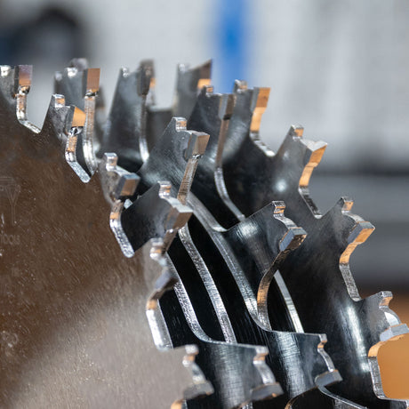 Close-up of a metal circular saw blade with teeth on a blurred background