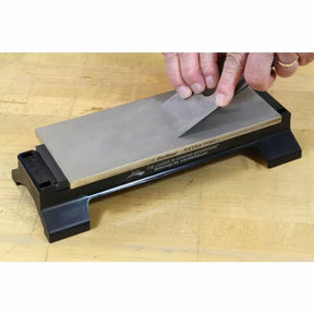 Sharpening a plane iron blade on a diamond sharpening stone atop a wooden workbench