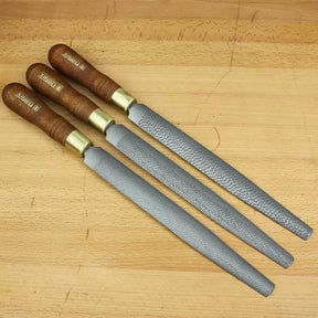 Set of three woodworking rasps with wooden handles on a wooden workbench