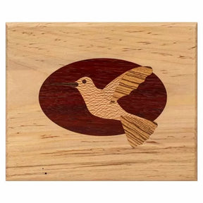 Woodworking inlay of a hummingbird in flight set in an oval on a light wood plaque