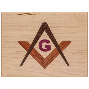 Wooden plaque with inlaid square, compass, and G symbol for woodworking decor.