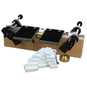 Woodworking joinery jig with black clamps, adjustment knobs, and plastic shims on white background