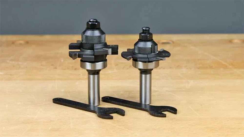 Two woodworking router bits with wrenches on a workbench, ideal for joinery and precision cuts