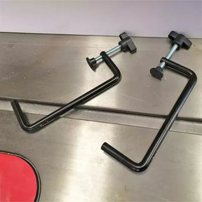 Pair of metal woodworking clamps on a workbench, ideal for securing materials.