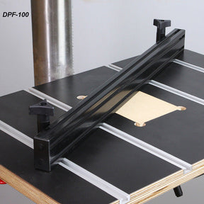 Drill press fence mounted on a woodworking table with T-slots for precision alignment.
