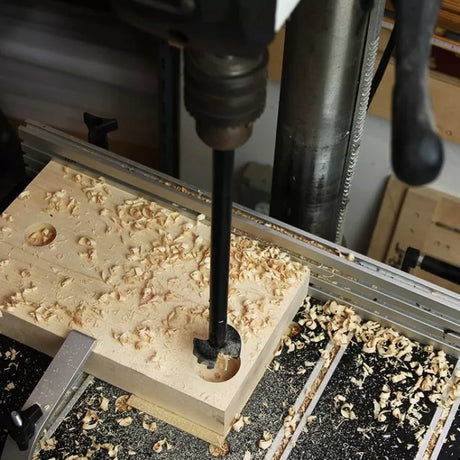 Drill press using forstner bit to bore clean hole in wood block, woodworking in progress