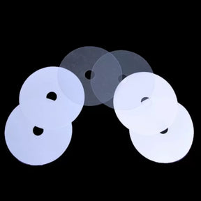 Set of six clear plastic shims for woodworking tools, round with center holes, on black background.