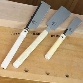 Three Japanese pull saws with labeled handles on a wooden workbench for woodworking.