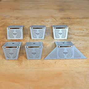 Set of six metal woodworking jigs with geometric patterns on a wooden workbench