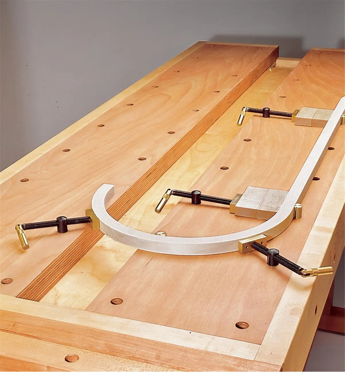 Woodworking clamping jig and curved template secured on a workbench