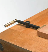 Brass woodworking holdfast clamp securing wood piece to workbench