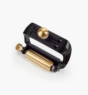 Woodworking honing guide tool with brass roller and black adjustable frame on white background
