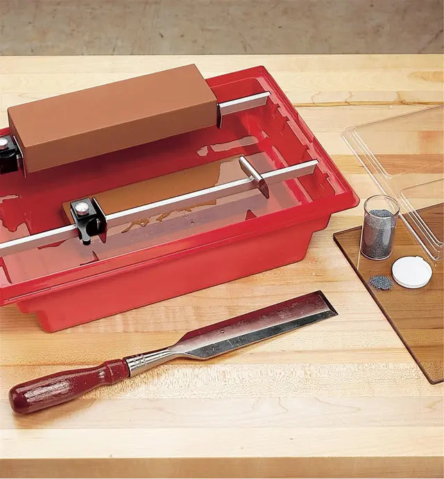 Chisel sharpening system with honing guide, water stone, and abrasive on workbench