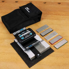 Chisel sharpening system with honing guide, diamond sharpening stones, and black carrying pouch on a wooden workbench.