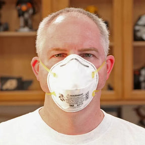 Man wearing N95 dust mask in woodworking shop for safety and respiratory protection