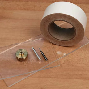 Woodworking template making kit with router bits, brass knob, acrylic sheets, and tape on workbench