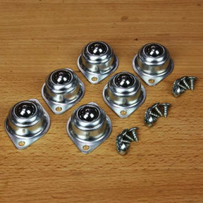 Set of six metal ball transfer units with mounting screws on wooden surface
