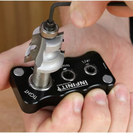 Person adjusting woodworking router bit with bearing using Allen wrench and setup jig