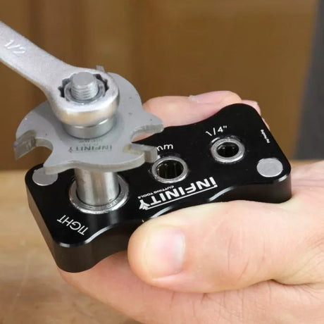 Hand using router bit tightening jig with wrench on woodworking tool