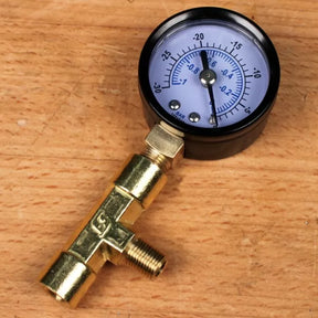 Vacuum pressure gauge with brass fittings on a wooden workbench