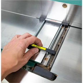 Hand adjusting jointer blade height gauge on metal woodworking jointer table